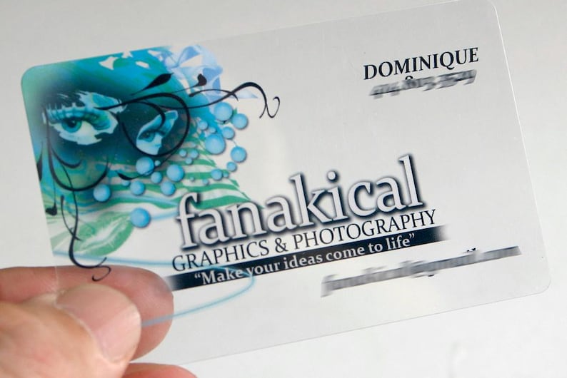 Puede incluir: Una tarjeta de visita rectangular semitransparente con un dise&ntilde;o gr&aacute;fico azul y negro de un ojo y remolinos abstractos. El texto dice "DOMINIQUE", "fanakical GRAPHICS & PHOTOGRAPHY" y el eslogan "Make your ideas come to life".