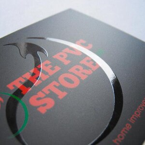 May include: A rectangular black business card with a matte finish featuring a glossy, raised black circular graphic. The text THE PVC STORE is printed in red, and the phrase home improvement needs! is printed in red on the bottom right corner.