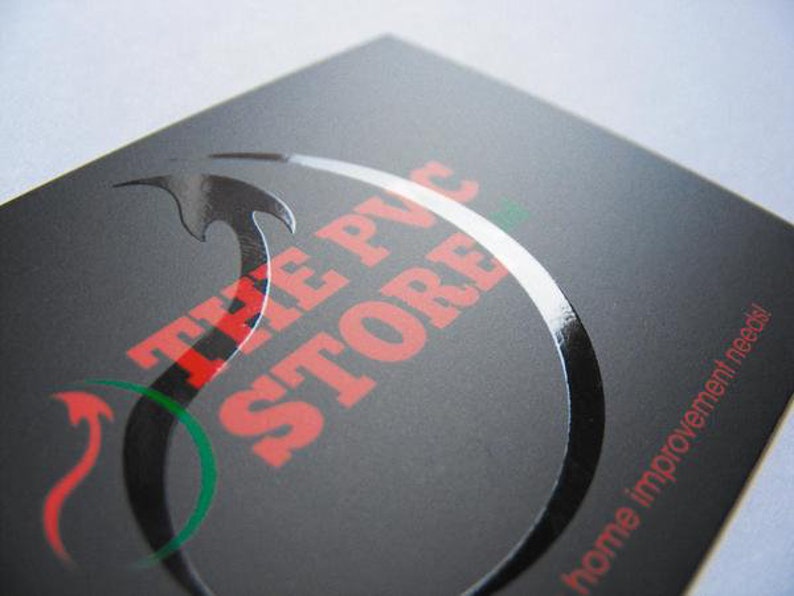 May include: A rectangular black business card with a matte finish featuring a glossy, raised black circular graphic. The text THE PVC STORE is printed in red, and the phrase home improvement needs! is printed in red on the bottom right corner.