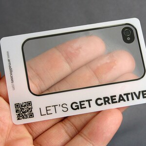 Może przedstawiać: Biała plastikowa karta z przezroczystym okienkiem, kt&oacute;re pokazuje palec przez obiektyw etui na telefon. Na karcie nadrukowany jest tekst "LET'S GET CREATIVE."