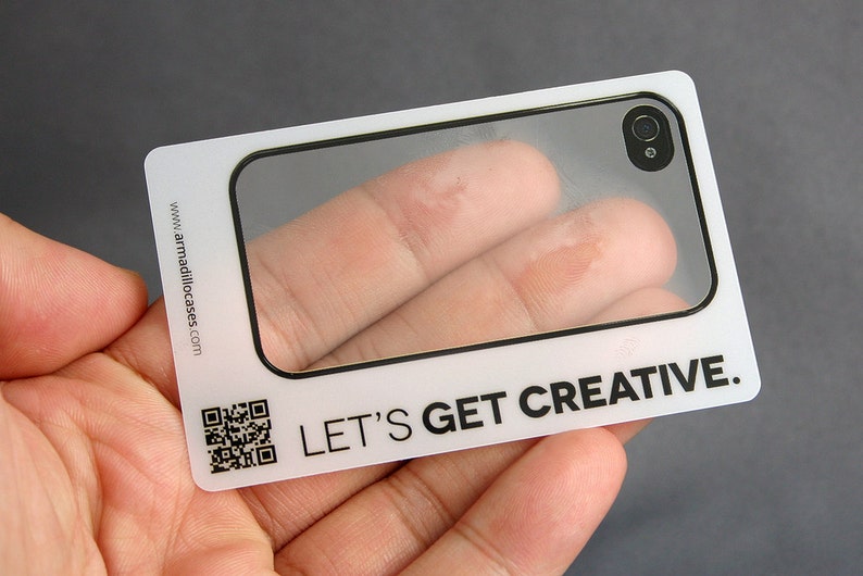 Może przedstawiać: Biała plastikowa karta z przezroczystym okienkiem, kt&oacute;re pokazuje palec przez obiektyw etui na telefon. Na karcie nadrukowany jest tekst "LET'S GET CREATIVE."