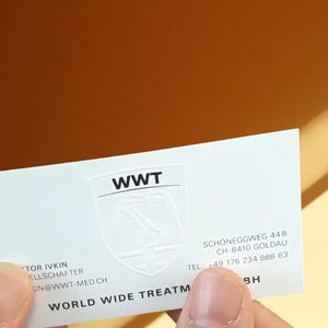 May include: A white rectangular business card featuring the black text WWT above a subtle embossed shield logo. The card includes the address Schoneggweg 44 B, CH-6410 Goldau, the phone number +49 176 234 888 63, and the text World Wide Treatment.