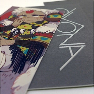 May include: A stack of cards featuring an illustration of a person with a red dot on their forehead, wearing a colorful patterned jacket and white fur trim. The card on the right has the word "ZONA" in silver lettering.