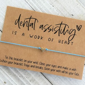 Peut inclure: Un bracelet en cordon bleu clair avec un charm en forme de c&oelig;ur argent&eacute; et une carte qui dit "dental assisting is a work of heart" avec un petit symbole de c&oelig;ur. La carte comprend &eacute;galement des instructions pour attacher le bracelet &agrave; votre poignet, fermer les yeux, faire un v&oelig;u et lorsque le bracelet s'effiloche et se casse, votre v&oelig;u se r&eacute;alisera.
