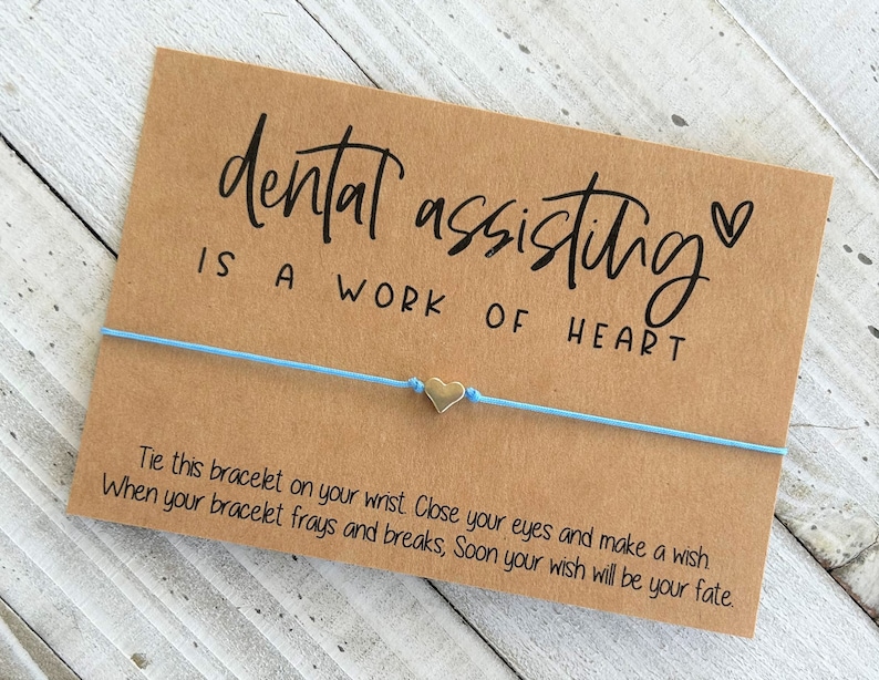 Peut inclure: Un bracelet en cordon bleu clair avec un charm en forme de c&oelig;ur argent&eacute; et une carte qui dit "dental assisting is a work of heart" avec un petit symbole de c&oelig;ur. La carte comprend &eacute;galement des instructions pour attacher le bracelet &agrave; votre poignet, fermer les yeux, faire un v&oelig;u et lorsque le bracelet s'effiloche et se casse, votre v&oelig;u se r&eacute;alisera.