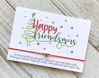 May include: Red string bracelet with a gold star charm and a card that says "Happy Friendsmas" with a green and red stylized Christmas tree and stars. The card also includes instructions to tie the bracelet on your wrist, close your eyes, make a wish, and when the bracelet frays, your wish will come true.
