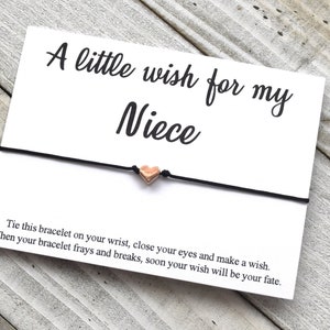 May include: A card with the text "A little wish for my Niece" and a black string bracelet with a small heart charm. The card also includes instructions on how to use the bracelet.
