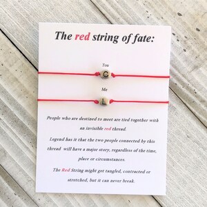 May include: Two red string bracelets with gold beads that spell out "You" and "Me". The card reads "The red string of fate: People who are destined to meet are tied together with an invisible red thread. Legend has it that the two people connected by this thread will have a major story, regardless of the time, place or circumstances. The Red String might get tangled, contracted or stretched, but it can never break."