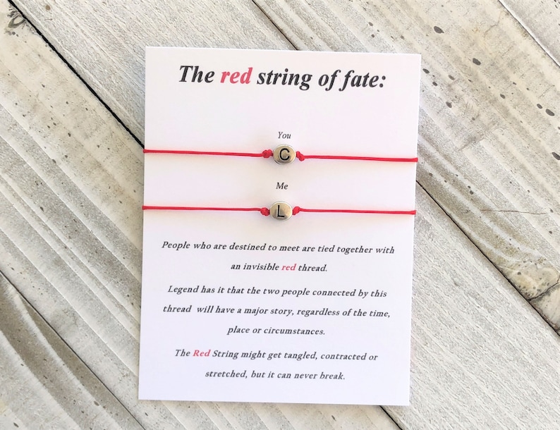 May include: Two red string bracelets with gold beads that spell out "You" and "Me". The card reads "The red string of fate: People who are destined to meet are tied together with an invisible red thread. Legend has it that the two people connected by this thread will have a major story, regardless of the time, place or circumstances. The Red String might get tangled, contracted or stretched, but it can never break."
