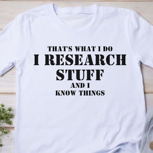 May include: White t-shirt with black text that reads "That's what I do I research stuff and I know things."