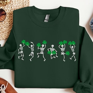 May include: A dark green sweatshirt with a graphic of five skeletons holding shamrocks. The skeletons are dancing and smiling.