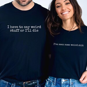 May include: Two black t-shirts with white text. One shirt reads "I have to say weird stuff or I'll die," and the other says "I've seen some weird shit." Both shirts are paired with blue jeans.
