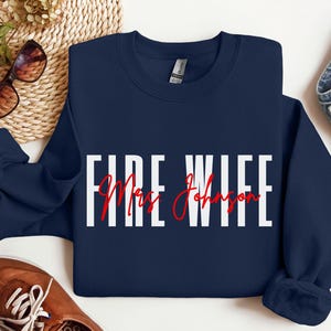 May include: Navy blue sweatshirt with the text "FIRE WIFE" in white letters and "Mrs. Johnson" in red cursive writing.