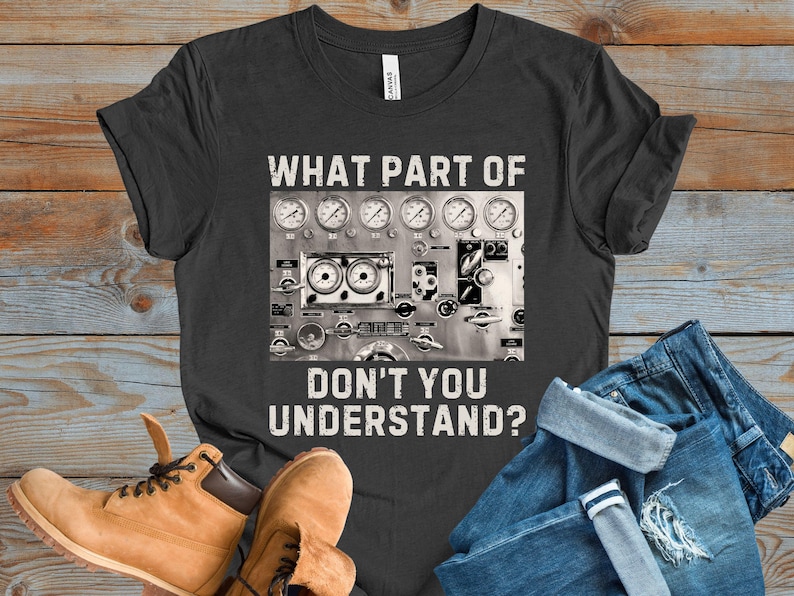 May include: A dark gray t-shirt with a distressed white graphic of a control panel with gauges and the text "WHAT PART OF DON'T YOU UNDERSTAND?"