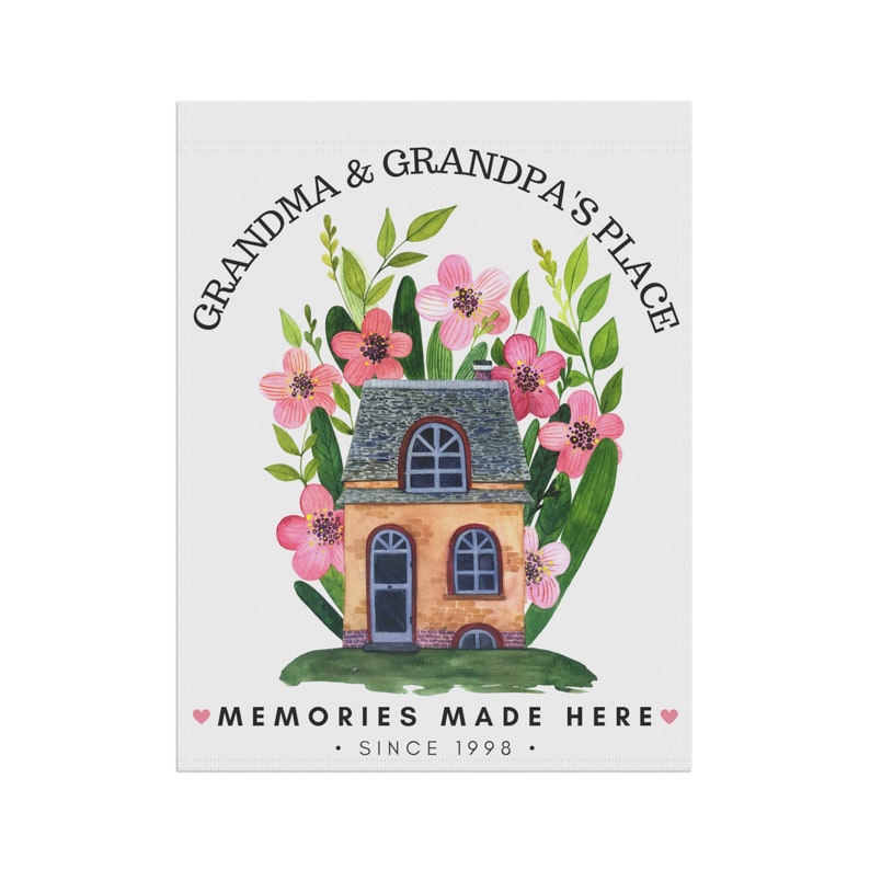 May include: A watercolor illustration of a house with a brown brick exterior and a gray roof. The house is surrounded by pink flowers and green leaves. The text "Grandma & Grandpa's Place" is written in a circle above the house. The text "Memories Made Here. Since 1998." is written below the house.