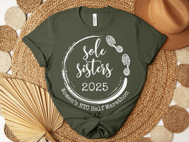 May include: A green t-shirt with a white circle design that says "Sole Sisters 2025 Women's NYC Half Marathon" with a footprint graphic.