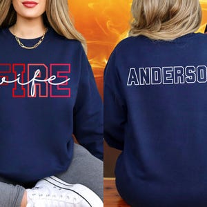 May include: Navy blue sweatshirt with the word "FIRE" in red block letters and "wife" in white script. The back of the sweatshirt displays the name "ANDERSON" in white block letters.