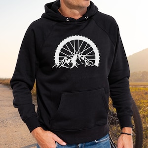 May include: Black hooded sweatshirt with a white graphic of a mountain range with a bicycle wheel in the background.