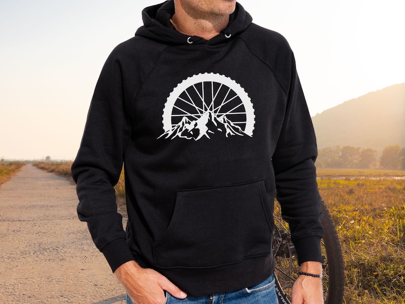 May include: Black hooded sweatshirt with a white graphic of a mountain range with a bicycle wheel in the background.