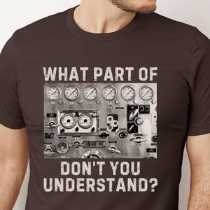 May include: A brown t-shirt with a graphic of a control panel with gauges and the text "WHAT PART OF DON'T YOU UNDERSTAND?"