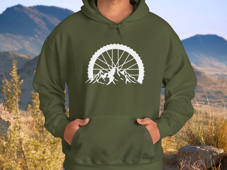 May include: A green hooded sweatshirt with a white graphic of a mountain range with a bicycle wheel in the center.