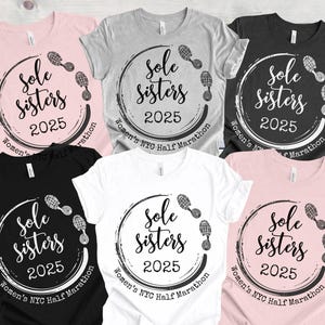 May include: Six t-shirts in different colors with a white circle design that says "Sole Sisters 2025" with footprints around the circle. The text "Women's NYC Half Marathon" is written below the circle.
