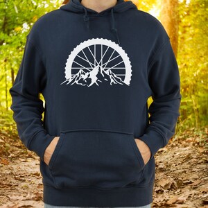 May include: A navy blue hoodie with a white graphic of a mountain range with a bicycle wheel in the background.