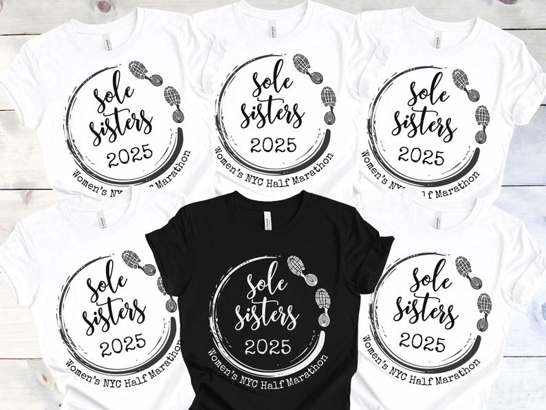 May include: Five white t-shirts with black text and graphics. The text reads "Sole Sisters 2025 Women's NYC Half Marathon". The graphic is a circle with footprints around it.