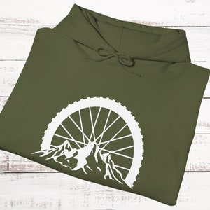 May include: A green hooded sweatshirt with a white mountain silhouette and bicycle wheel design.