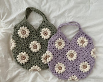 May include: Two crocheted bags with daisy flower designs. One bag is green and the other is purple.