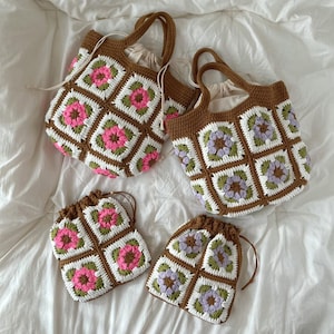 May include: Four crochet bags and pouches. The bags have brown handles and trim, with white, pink, green, and brown floral patterns. The pouches have drawstring closures. The items are arranged on a white surface.