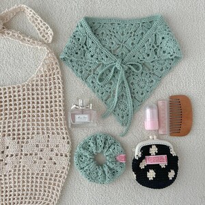 May include: An assortment of handmade accessories, including a crocheted tote bag, a mint green crocheted neck wrap, a scrunchie, and a small coin purse with a floral pattern. Also includes a perfume bottle, lip balm, and a wooden comb.