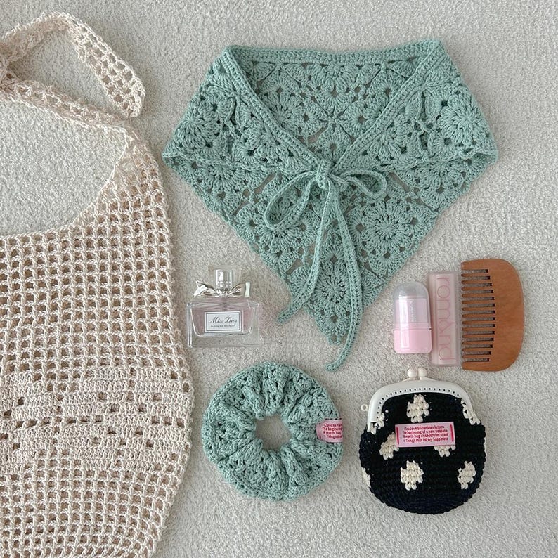 May include: An assortment of handmade accessories, including a crocheted tote bag, a mint green crocheted neck wrap, a scrunchie, and a small coin purse with a floral pattern. Also includes a perfume bottle, lip balm, and a wooden comb.