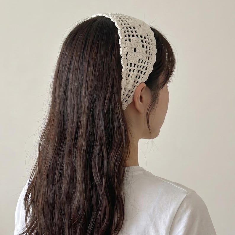 Puede incluir: Diadema de ganchillo color crema. La diadema est&aacute; hecha de un material tejido de tejido abierto. La diadema se lleva en la cabeza y es visible desde un lado, con cabello largo y casta&ntilde;o oscuro que fluye por la espalda. La persona lleva una camiseta blanca.