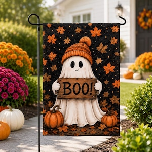 A Halloween-themed garden flag featuring a ghost holding a sign that says "Boo!" against a backdrop of autumn leaves and pumpkins.
