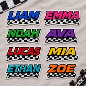 May include: Eight rectangular embroidered patches featuring names in bold, colored block letters above a black and white checkered racing flag design. The names include Liam in blue, Emma in pink, Noah in green, Ava in purple, Lucas in red, Mia in yellow, Ethan in teal, and Zoe in orange.