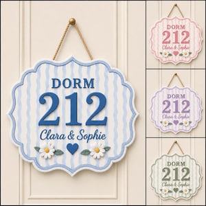 May include: A scalloped wall sign featuring a wavy striped pattern, the text DORM 212, the names Clara & Sophie, two white daisy flowers, and a blue heart. The sign is suspended by a tan rope and is available in blue, pink, purple, and green.