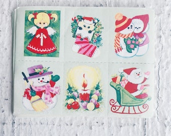 Könnte beinhalten: Eine Bogen mit Vintage-Weihnachtsaufklebern mit verschiedenen weihnachtlichen Motiven, darunter ein Schneemann, ein Engel, ein Strumpf, eine Kerze und der Weihnachtsmann im Schlitten. Die Aufkleber sind auf weißem Hintergrund mit bunten Illustrationen gedruckt.