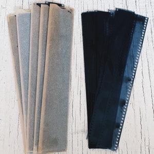 May include: Two stacks of photographic film negatives. One stack is wrapped in brown paper and the other is a stack of black and white negatives.