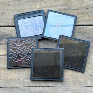 May include: Five black framed glass slides with different images. The images include a grid pattern, a bird in flight, a pattern of white lines on a brown background, a blurry image, and a dark image.
