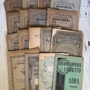 May include: A collection of vintage Grand Opera librettos, featuring various covers with text and illustrations. The covers are primarily beige and off-white, with some green accents. Titles include "Aida" and "Cavalleria Rusticana".