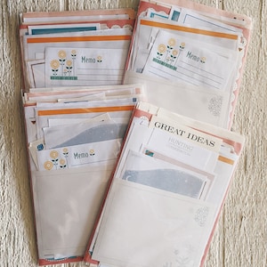 May include: Three stacks of colorful memo pads with sunflower and snowflake designs. The top memo pad has the text "Memo" printed on it. The middle memo pad has the text "Memo" printed on it. The bottom memo pad has the text "GREAT IDEAS HUNTING CONSERVATION" printed on it.