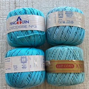 May include: Four balls of light blue yarn labelled "Pingouin Fil d'Écosse N°3". The yarn is made in Brazil and is machine washable. The label also includes information about the yarn's weight, length, and needle size.