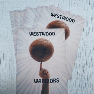 Könnte beinhalten: Ein Stapel Karten mit einer Basketballgrafik und dem Text "Westwood Warriors" auf der Vorderseite. Der Basketball ist braun und hat den Schriftzug "Basketball" aufgedruckt.