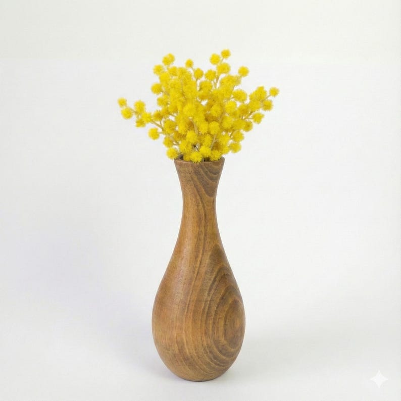 Puede incluir: Un jarr&oacute;n de madera con cuello estrecho y cuerpo redondeado contiene un vibrante ramo de flores amarillas. El jarr&oacute;n tiene un acabado de veta de madera natural, y las flores son de un amarillo brillante y alegre. El arreglo est&aacute; sobre un fondo blanco.
