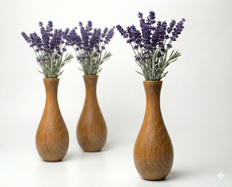 Puede incluir: Tres jarrones de madera con acabado marr&oacute;n claro, cada uno con un ramo de lavanda morada. Los jarrones tienen forma de l&aacute;grima con cuello estrecho. El fondo es blanco.