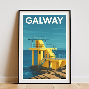 May include: Framed art print depicting a yellow diving board structure with blue railings and stairs, set against a blue sea and sky. The word "GALWAY" is printed in white at the top. The artwork is displayed on a wooden floor.