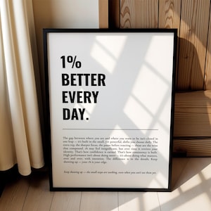 Może przedstawiać: Oprawiony pionowy wydruk ścienny z pogrubionym czarnym napisem 1% BETTER EVERY DAY. Pod głównym nagłówkiem znajduje się pozioma linia, a po niej akapit mniejszego czarnego tekstu dotyczącego konsekwencji i rozwoju osobistego.