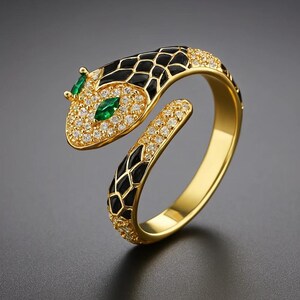 Könnte beinhalten: Goldfarbener Schlangenring mit schwarzen Emaille-Details und besetzt mit kleinen, klaren Kristallen. Der Schlangenkopf hat zwei grüne Smaragdsteine als Augen.