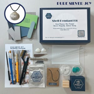 Könnte beinhalten: Ein Muschel-Anhänger-Set mit verschiedenen Werkzeugen, Materialien und einem fertigen silbernen Muschel-Anhänger. Das Set enthält Pinsel, ein Poliertuch und eine Schritt-für-Schritt-Anleitung. Auf der Box steht "Shell Pendant Kit" und "Pure Silver Joy".